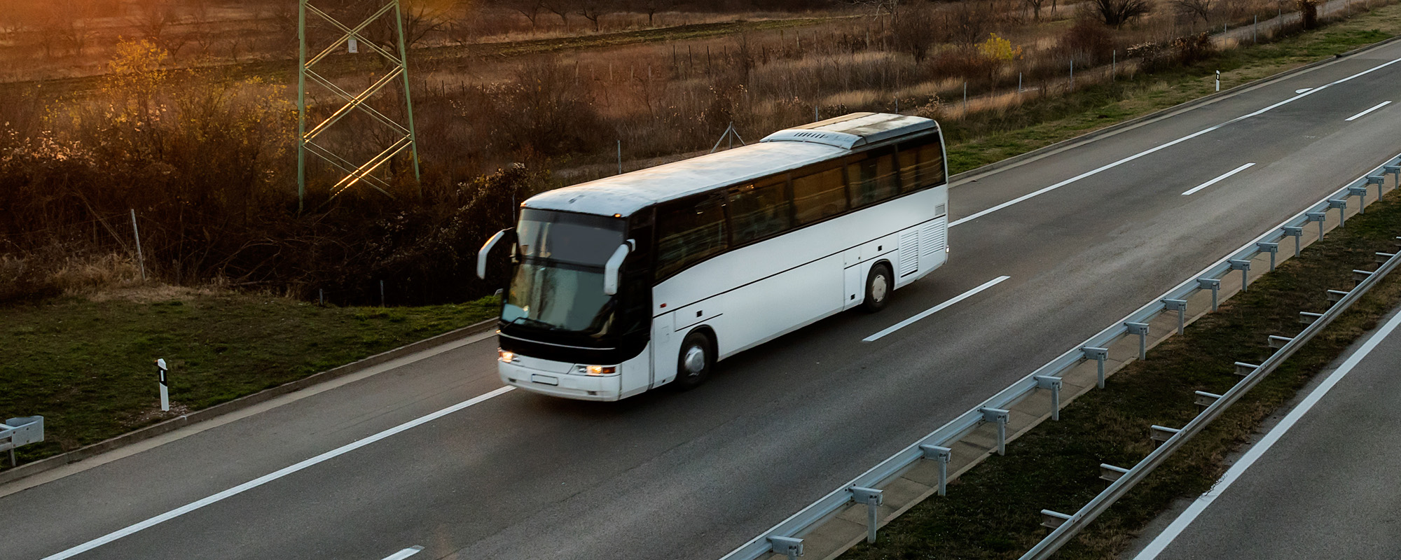 White bus traveling on a country highway