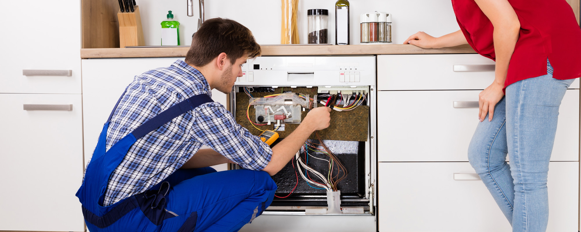 Woman Looking At Male Technician Checking Dishwasher